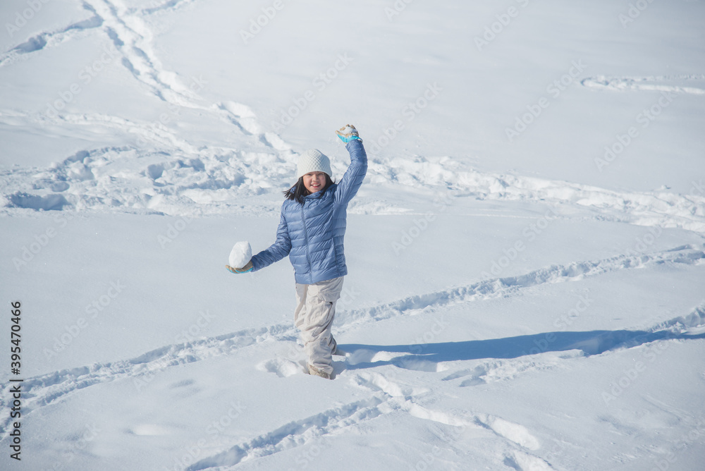 Happy asian girl smiling outdoors in snow on cold winter day