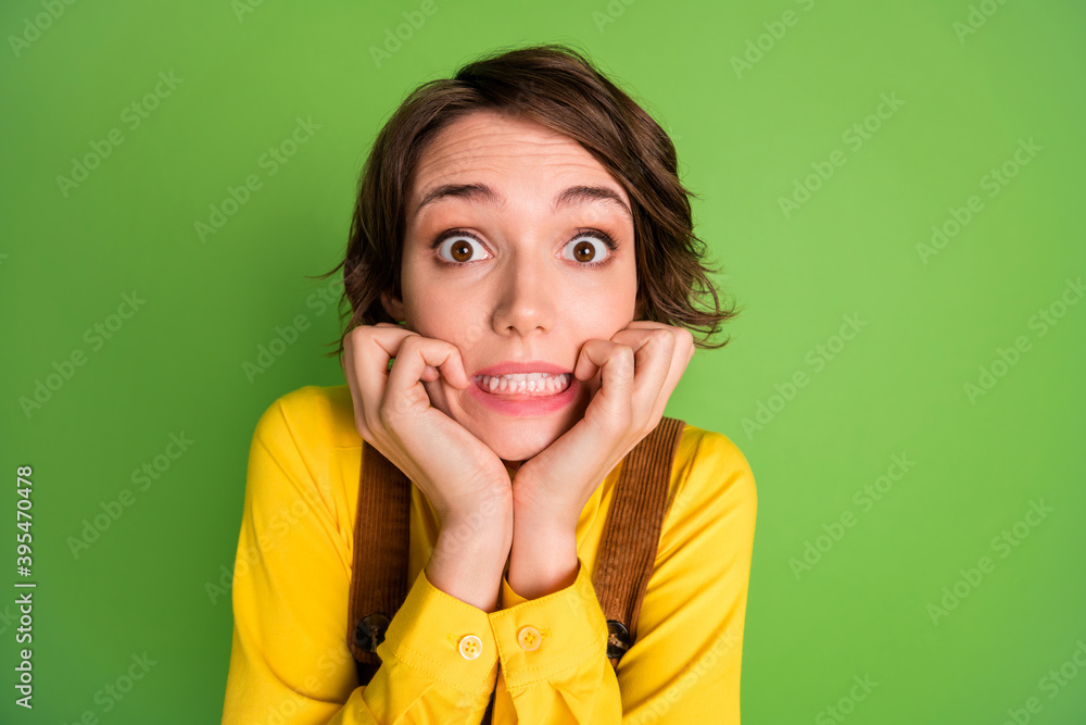Photo of anxious scared girl gnaw nails look camera wear yellow shirt overall isolated green color background Photo of anxious scared girl gnaw nails look camera wear yellow shirt overall isolated green color background