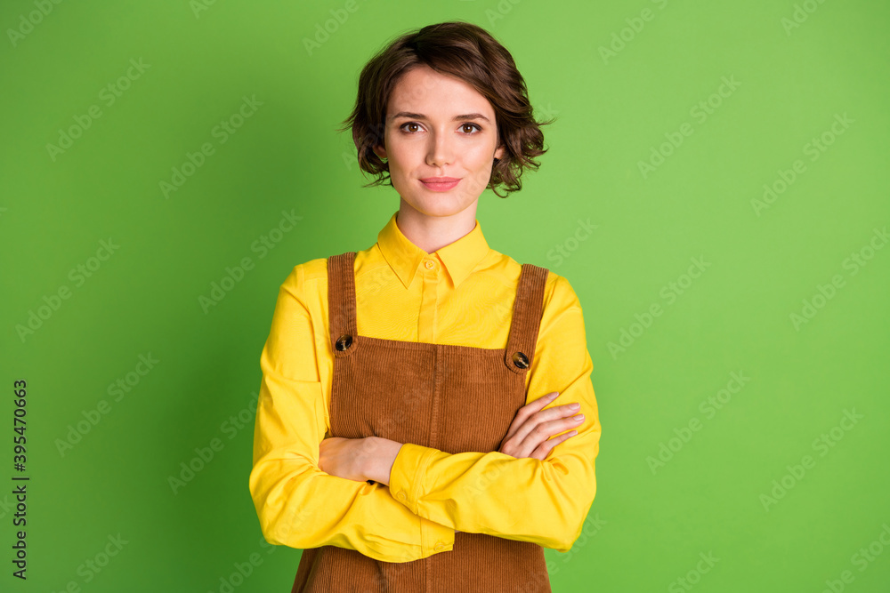Photo of self-assured young girl crossed arms look camera wear yellow shirt overall isolated green color background Photo of self-assured young girl crossed arms look camera wear yellow shirt overall isolated green color background
