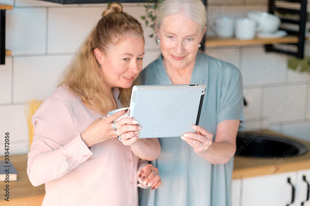 old mom and middle-aged daughter take selfies and talk via video link. Senior woman with her daughter looking at modern gadget indoors. relaxing together, different generations hobby pastime. old mom and middle-aged daughter take selfies and talk via video link. Senior woman with her daughter looking at modern gadget indoors. relaxing together, different generations hobby pastime.