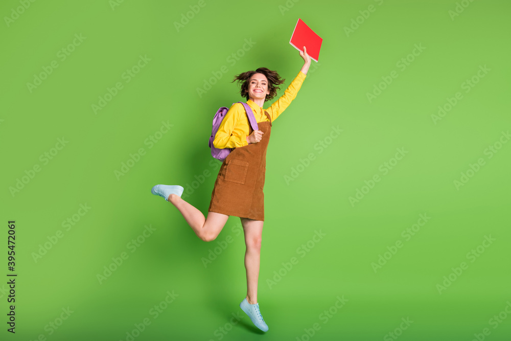 Full size profile photo of pretty nice brunette girl jumping hold planner rucksack wear brown dress sneakers isolated on green background Full size profile photo of pretty nice brunette girl jumping hold planner rucksack wear brown dress sneakers isolated on green background