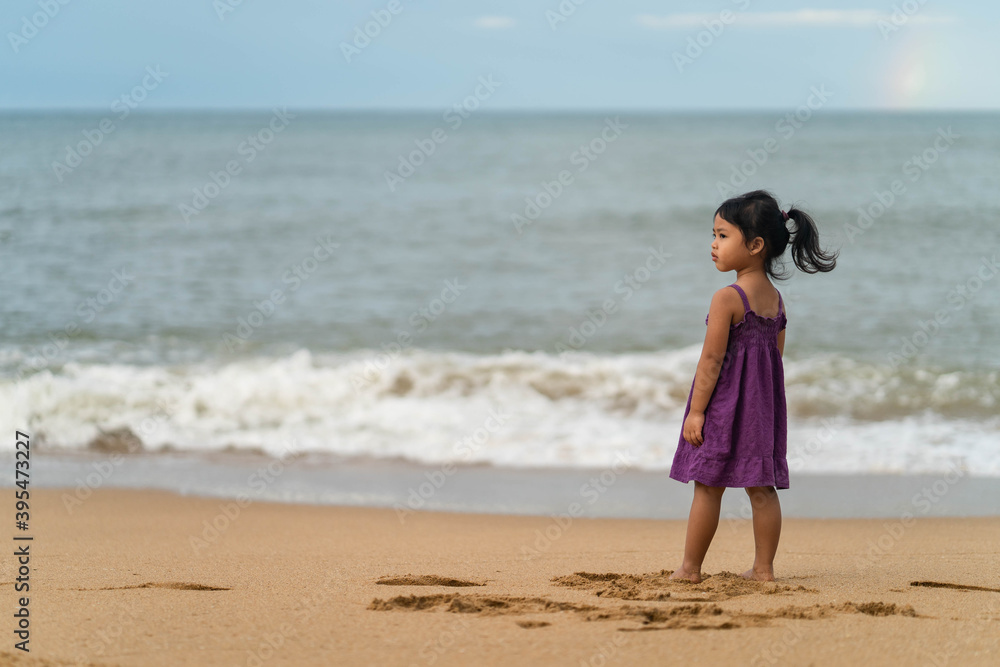 Cute little girl playing on the beach in morning.