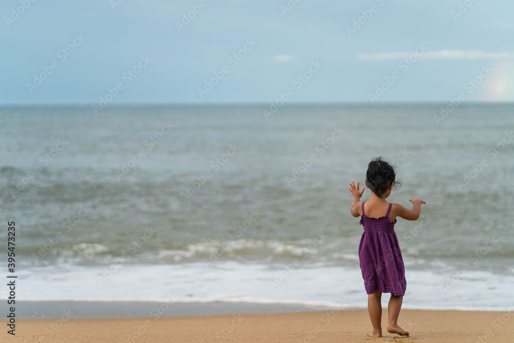 Cute little girl playing on the beach in morning.