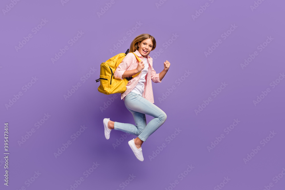 Full size profile photo of hooray pretty girl jump run wear pink shirt jeans sneakers rucksack isolated on violet background Full size profile photo of hooray pretty girl jump run wear pink shirt jeans sneakers rucksack isolated on violet background