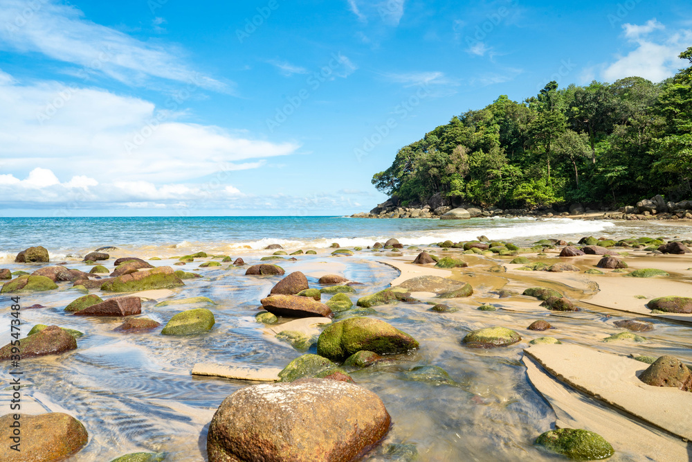 seashore with rocks against tiny cloud blue sky.