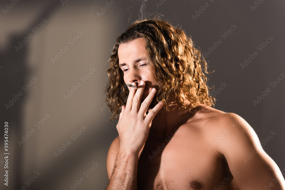 shirtless man with long hair smoking on dark background shirtless man with long hair smoking on dark background