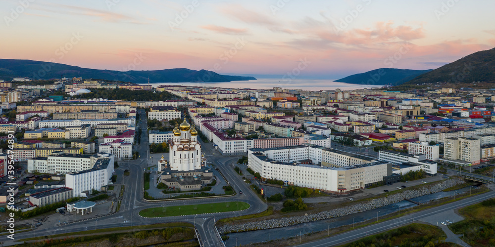 Beautiful panorama of the city of Magadan. Morning aerial view of the cathedral, streets, buildings, mountains and sea bay. A large port city in the Russian Far East. Magadan, Magadan Region, Siberia.