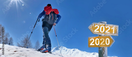 2021 and 2020  written on a postsign with a man in  touring ski climbing mountain photo