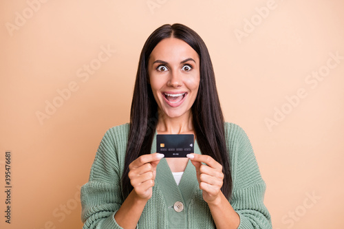 Photo of impressed girl hold card wear green sweater isolated on peach color background