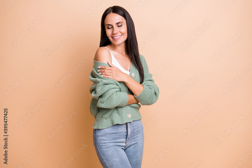 Photo of adorable cheerful woman closed eyes self hug comfort cardigan isolated on pastel beige color background Photo of adorable cheerful woman closed eyes self hug comfort cardigan isolated on pastel beige color background