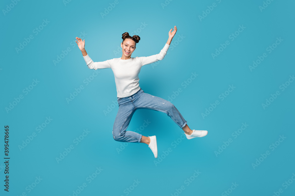 Full length photo of girl jump careless dance wear white pullover jeans footwear isolated blue color background