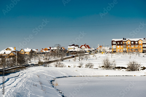 Multi-storey residential buildings made of white and red brick with plastic Windows, stand in winter under a layer of white lush snow in frosty Sunny weather.
