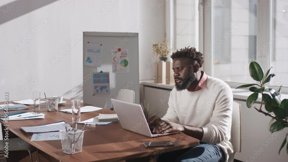 African American man sitting alone in office room sharing his ideas about business project during online meeting video call African American man sitting alone in office room sharing his ideas about business project during online meeting video call