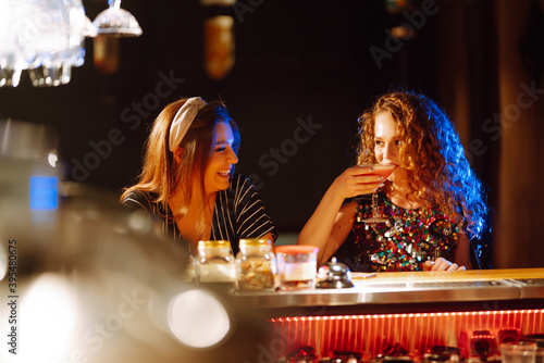 Canvas Print Cheerful women drinking cocktails in bar
