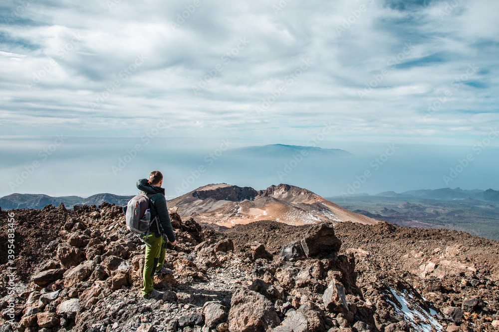 Young man at the top of El Teide volcano in Tenerife or mountain looking down the valley with splendid view. rater of Pico Viejo volcano