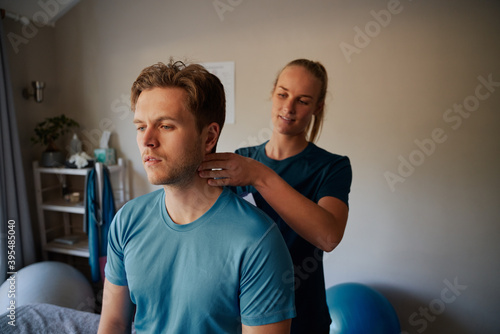 Tableau sur toile Young female physiotherapist giving neck massage to male patient in clinic