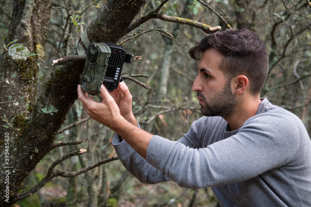A forester installs a photographic camera trap with infrared radiation and a motion detector in a tree, they photograph animals in the Mediterranean forest. Stock Photo | Adobe Stock A forester installs a photographic camera trap with infrared radiation and a motion detector in a tree, they photograph animals in the Mediterranean forest. Stock Photo | Adobe Stock