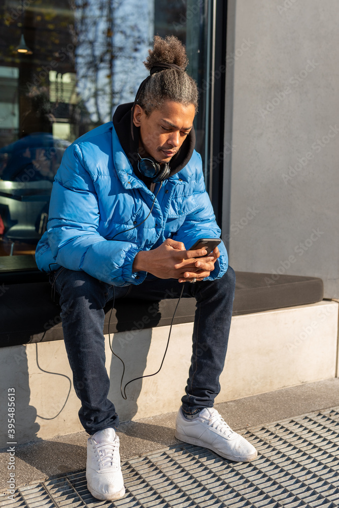 young afroamerican is surfing on social network with smartphone while sitting in front of a coffee shop, lifestyle concept of using new technology and device young afroamerican is surfing on social network with smartphone while sitting in front of a coffee shop, lifestyle concept of using new technology and device