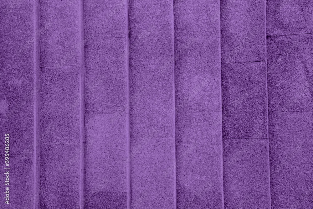 Fototapeta premium Surface of the wall with a decorative purple plaster. Textured purple concrete wall with vertical lines and stripes as a texture or background. Repair, design concept.