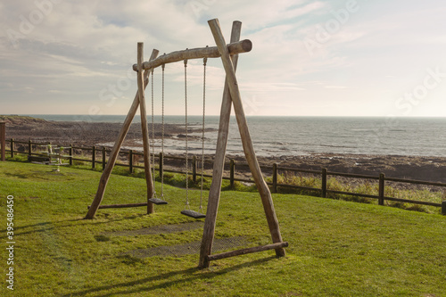 Two children's swings in a park by the seaside, at Crail, Fife, Scotland. The swings are empty, ready for the next two children to have some fun.