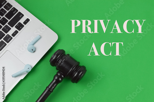 Top view of laptop, earphones and judge gavel over green background written with text PRIVACY ACT. 