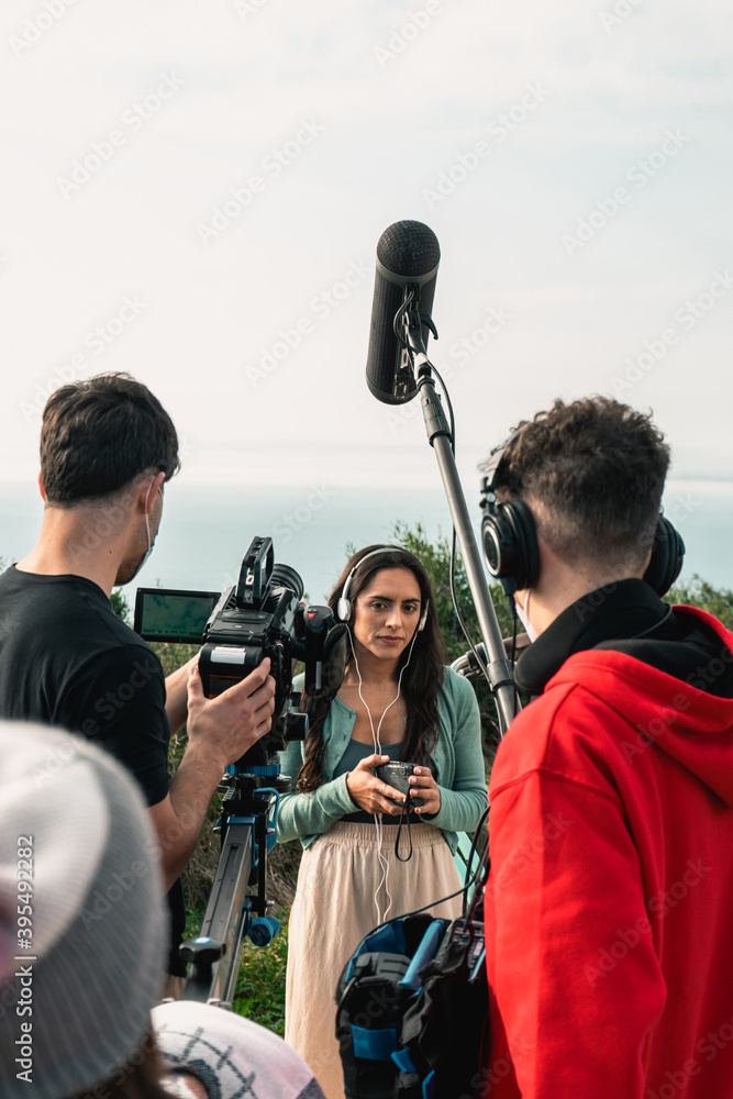 Behind the scenes of a filming for a movie. Camera operator, sound  technician and the actress in the middle Stock Photo
