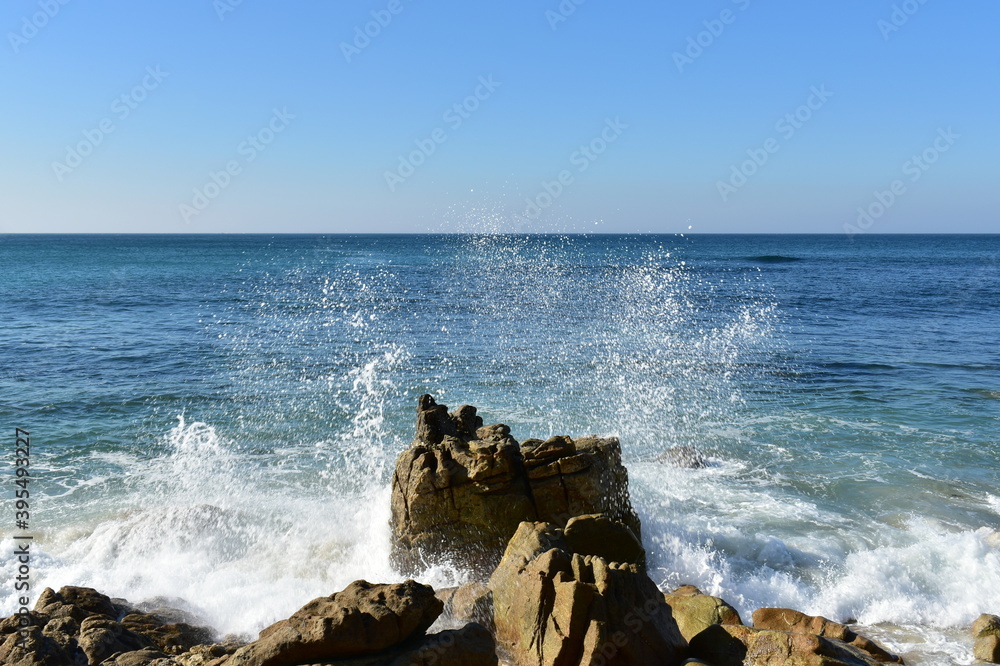 Waves breaking against the rocks with blue sky. Rias Baixas, Galicia, Spain.
