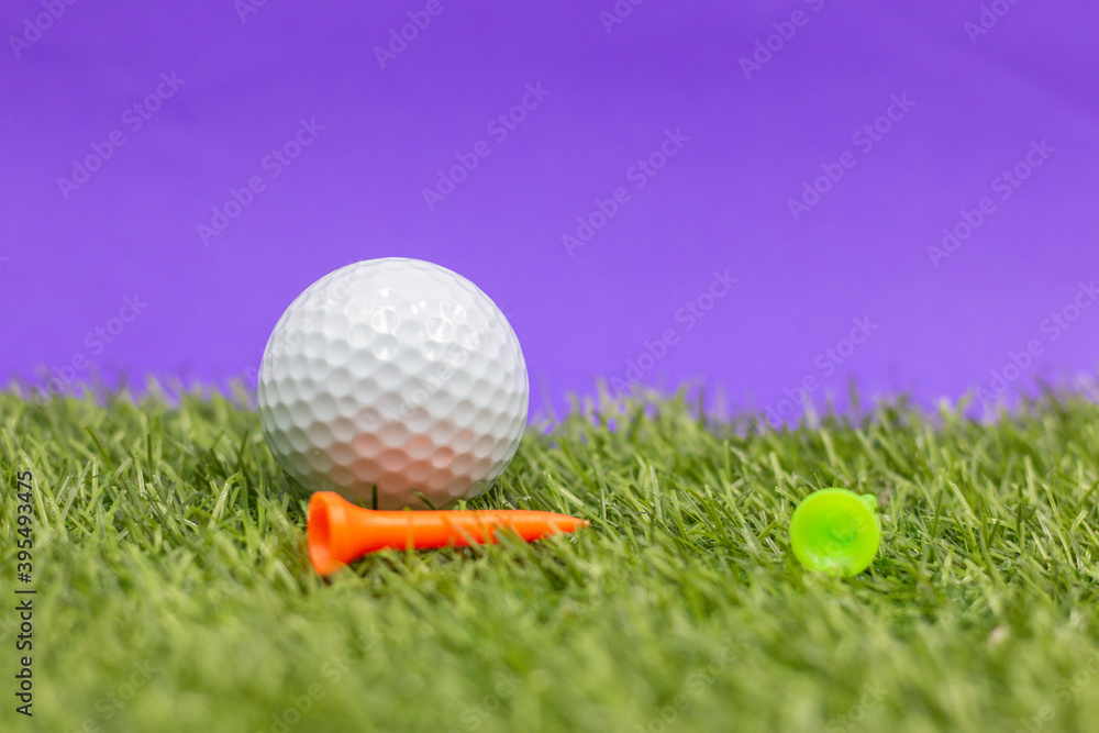 Naklejka premium Golf ball and tee are on purple background