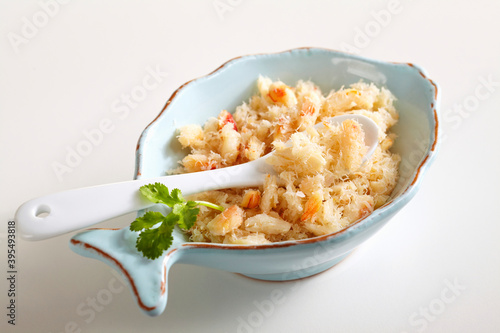 Shredded crab meat in a small bowl with a spoon and coriander leaves photo