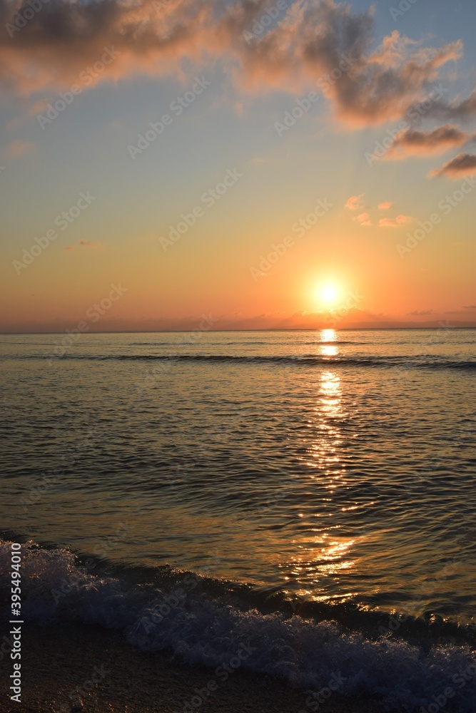 Golden reflection of sunset on the shore of a calm ocean
