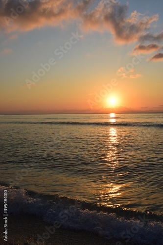Golden reflection of sunset on the shore of a calm ocean