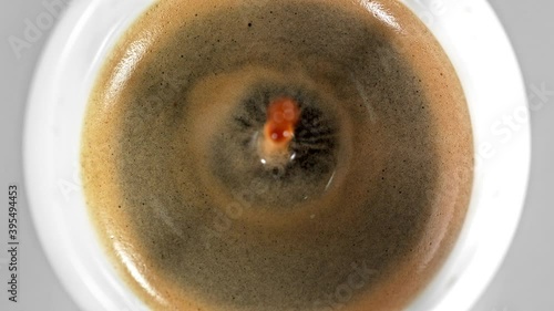 Super Slow Motion Detail Shot of Coffe Drop Falling into Fresh Espresso at 1000 fps. photo