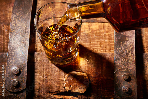 Bourbon pouring into rocks glass on a bourbon barrel
