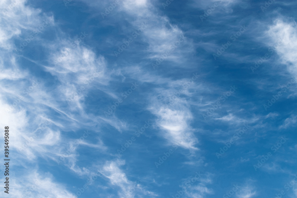 White feathery fluffy clouds on a blue sky, background and texture White feathery fluffy clouds on a blue sky, background and texture
