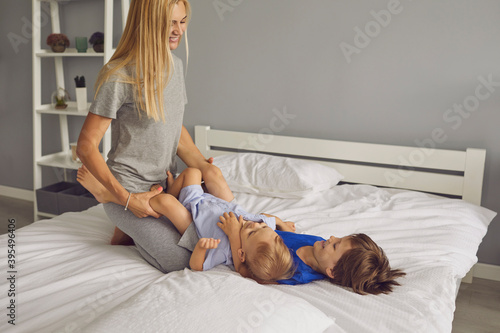 Happy woman mother playing with her children on bed in bedroom