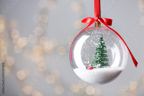 Cuadro en lienzo Decorative snow globe against blurred festive lights, closeup