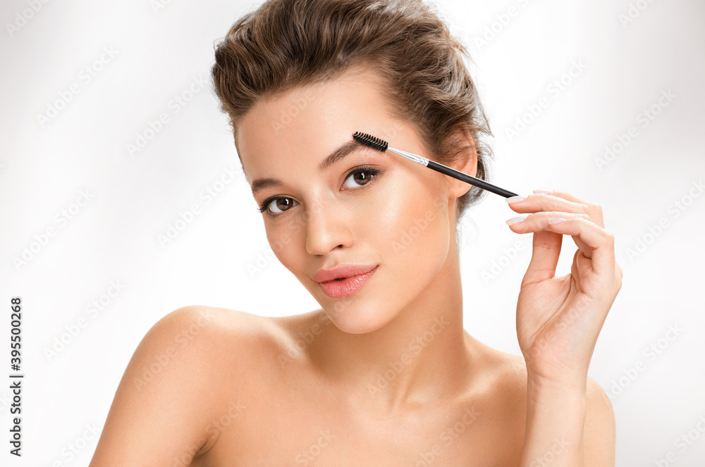 Young girl using brush for eyebrows. Photo of  girl with perfect makeup on white background. Beauty and skin care concept