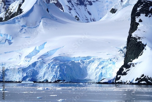 Summer landscape in Antarctica with melting snow, sea, icebergs, mountains