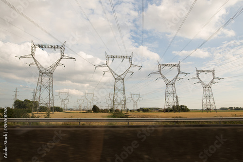 electricity cables lines by the side of a motor way collective together grouped with hay grass blue and cloudy skies, with some motion blur