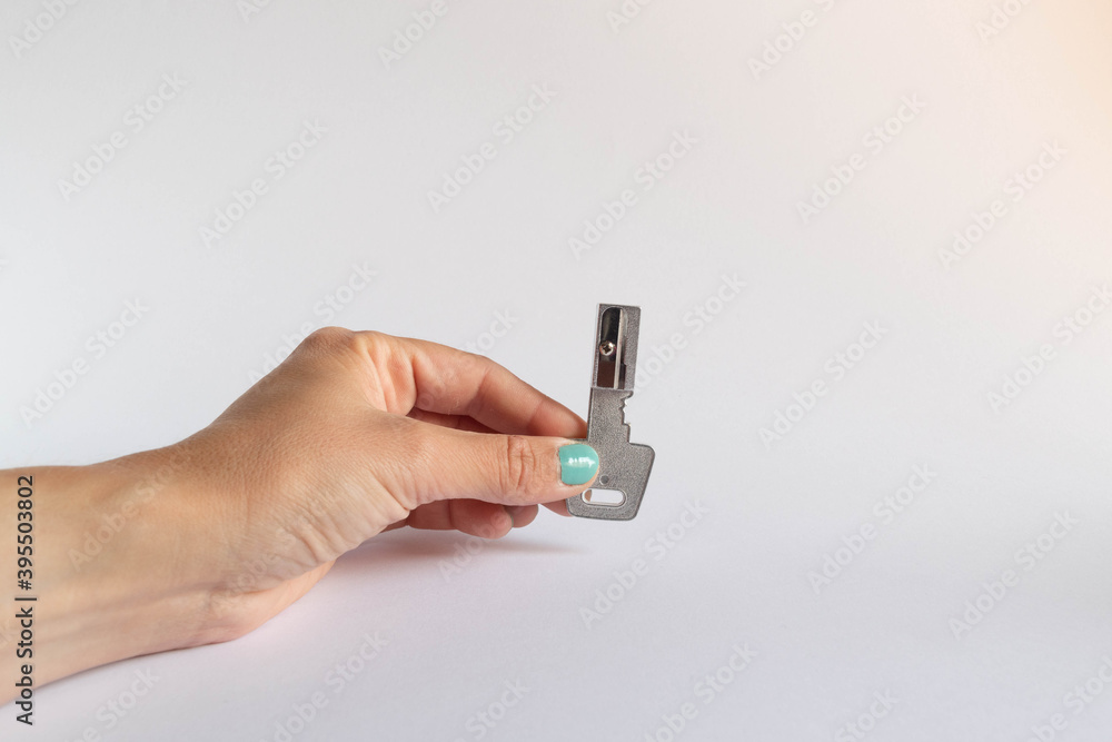 Hand holding a key shaped pencil sharpener on white background Hand holding a key shaped pencil sharpener on white background