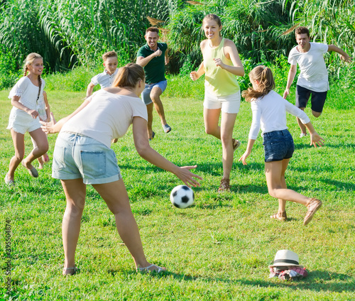 Happy family with kids having fun together outdoors playing football