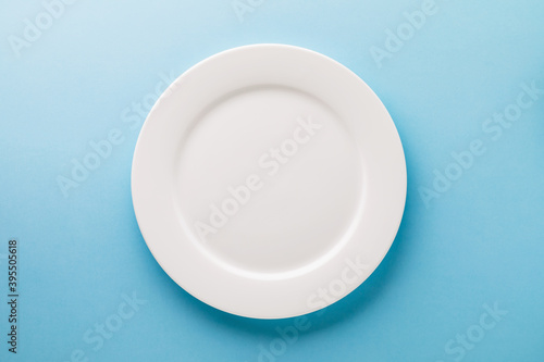 Flat ceramic plate white on a blue background, top view. Food background