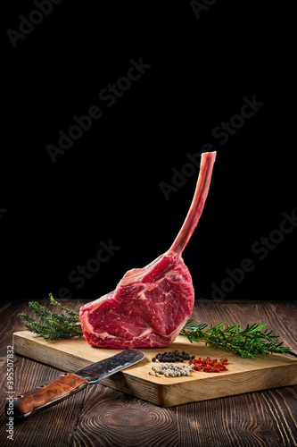 Quadro su tela Raw juicy cowboy steak on wooden cutting board with spice