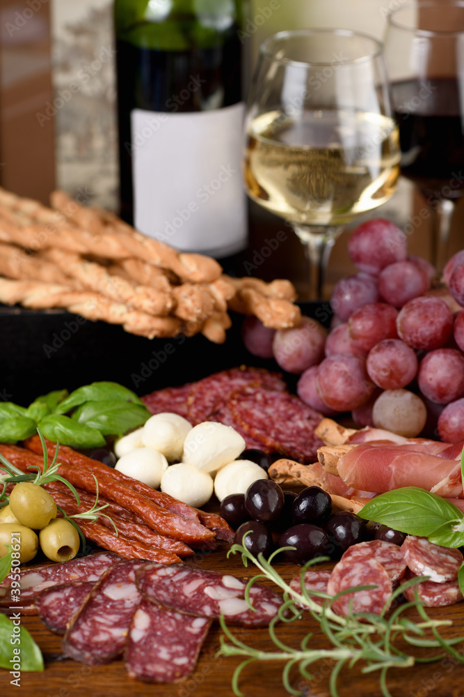 Antipasto. Dish with sausage, dried ham, salami, crispy grissini with grapes. A meat appetizer is a great idea for wine.