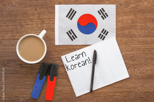 south korea national flag, cup of coffee, two markers, notebook with learn korean inscription on wooden table, study concept 