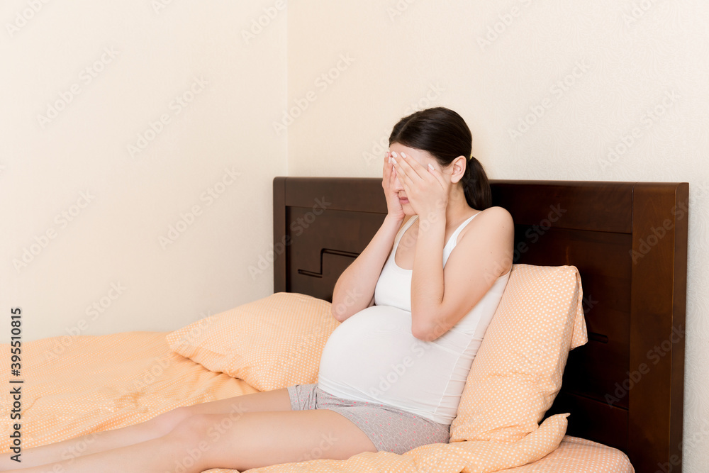 Young pretty pregnant woman suffering from headache at home in bed Young pretty pregnant woman suffering from headache at home in bed