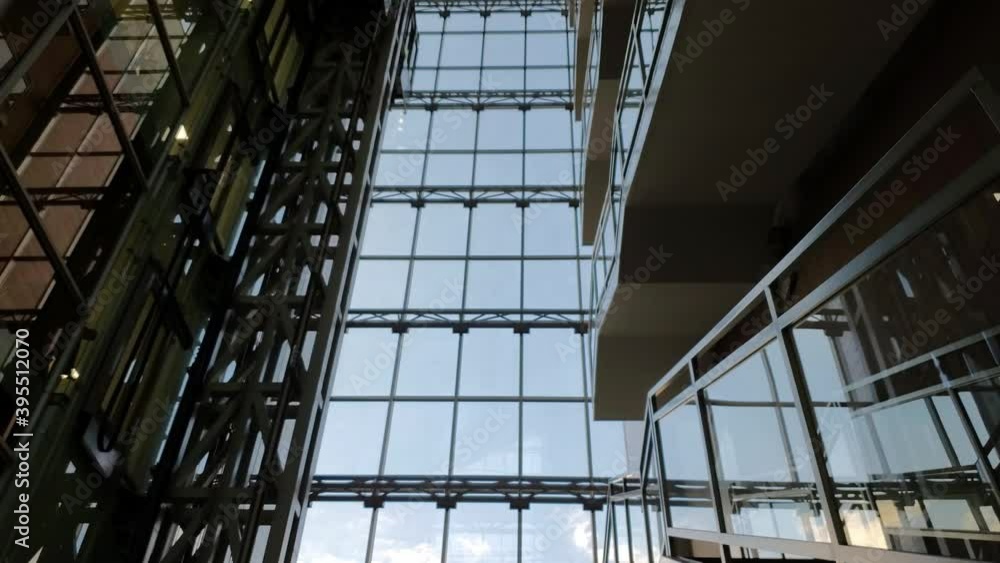White clouds float outside the corporate building window wall. Modern glass elevator rises up and goes down in time lapse. Abstract reflections in mirrored wall of business skyscraper. Urban timelapse White clouds float outside the corporate building window wall. Modern glass elevator rises up and goes down in time lapse. Abstract reflections in mirrored wall of business skyscraper. Urban timelapse