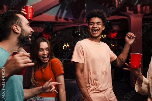 Canvas Print Group of happy young friends celebrating in the nightclub, dancing, drinking