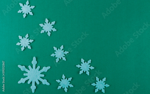 Large and small white snowflakes on a greenish background. Greenish background with white snowflakes