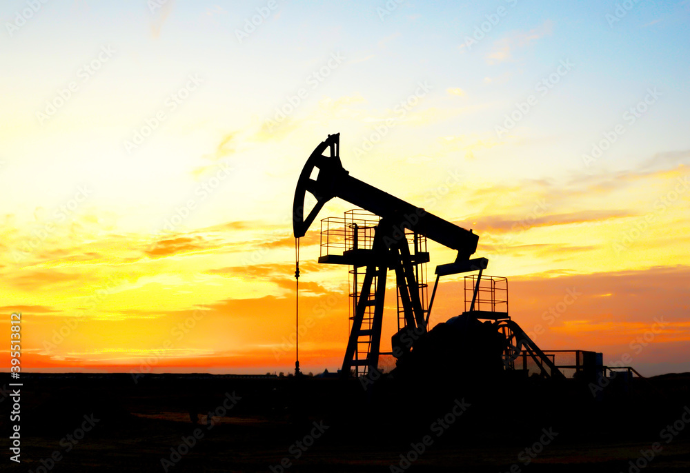 Crude oil pump jack at oilfield on atmospheric sunset backround. Fossil crude output and fuels oil production. Oil drill rig and drilling derrick. Global crude oil Prices, energy, petroleum demand